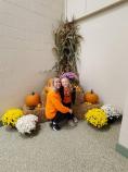 Kramer Homes Halloween party woman and child in front of cornstalks, hay bales, pumpkins, and chrysanthemums